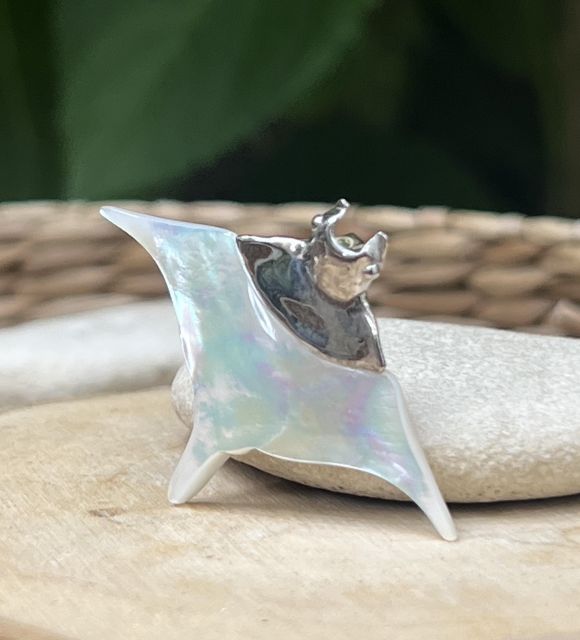 Pendentif raie manta en nacre blanche et argent rhodié, inspiré par les lagons polynésiens. Un bijou symbolique, aérien et lumineux.