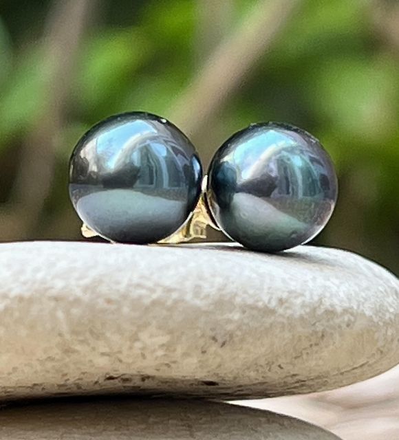 Deux perles rondes, d’un bleu violet intense, montées sur or jaune 18 carats. Leur lustre exceptionnel illumine le visage avec subtilité.