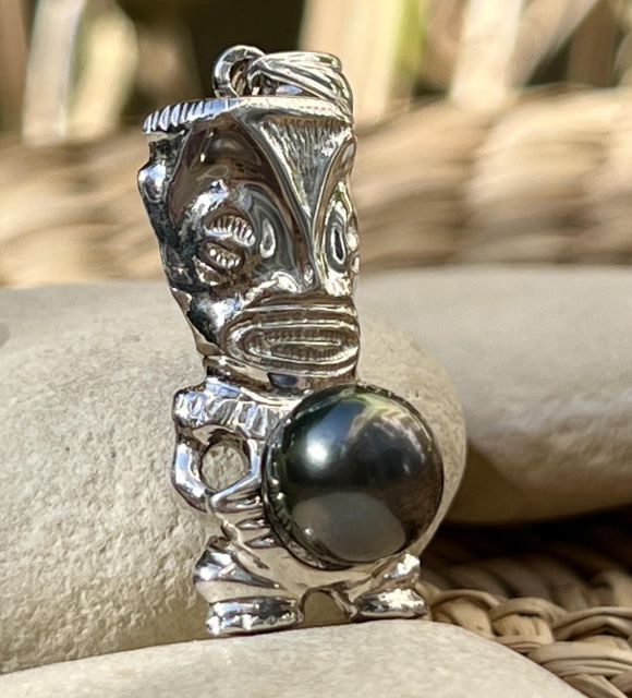 En argent rhodié, ce pendentif Tiki accueille une perle de Tahiti ronde de 9,84 mm, noire aux reflets pourpres uniques, classée AAA et au lustre très brillant.