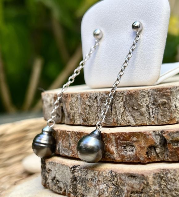 2 perles de Tahiti grises, comme deux éclats de lagon glissant le long d’un fil d’argent. Légères et lumineuses, elles dessinent la grâce à chaque mouvement.